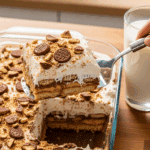 Glass dish of Chocolate Nutter Butter Icebox Cake being served with a spatula.