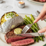 A beautiful plate of a homemade, elegant, and sliced Sirloin Steak with Garlic Butter, being served with a baked potato and roasted asparagus at a holiday dinner.