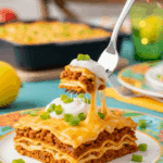 A beautiful plate of a homemade, elegant, and layered "Famous" Taco Lasagna, being served with a dollop of sour cream at a family dinner.