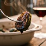 A close-up of a silver fork holding a crispy, roasted Brussels sprout dripping with a shiny balsamic glaze, with steam rising.A close-up of a silver fork holding a crispy, roasted Brussels sprout dripping with a shiny balsamic glaze, with steam rising.