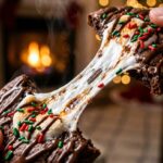 A close-up of a warm Hot Chocolate Cookie being pulled apart, revealing a long, perfect stretch of gooey melted marshmallow.