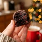 A close-up of a bitten Peppermint Oreo ball, showing the dark, rich cookie center and a smooth chocolate shell.