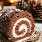 A close-up view of a slice of Yule Log cake showing a perfect chocolate-and-cream swirl pattern.