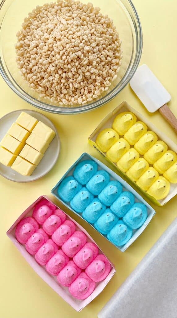 A flat lay showing chocolate chips, graham crackers, and colorful marshmallow Peeps arranged around an empty cast iron skillet.