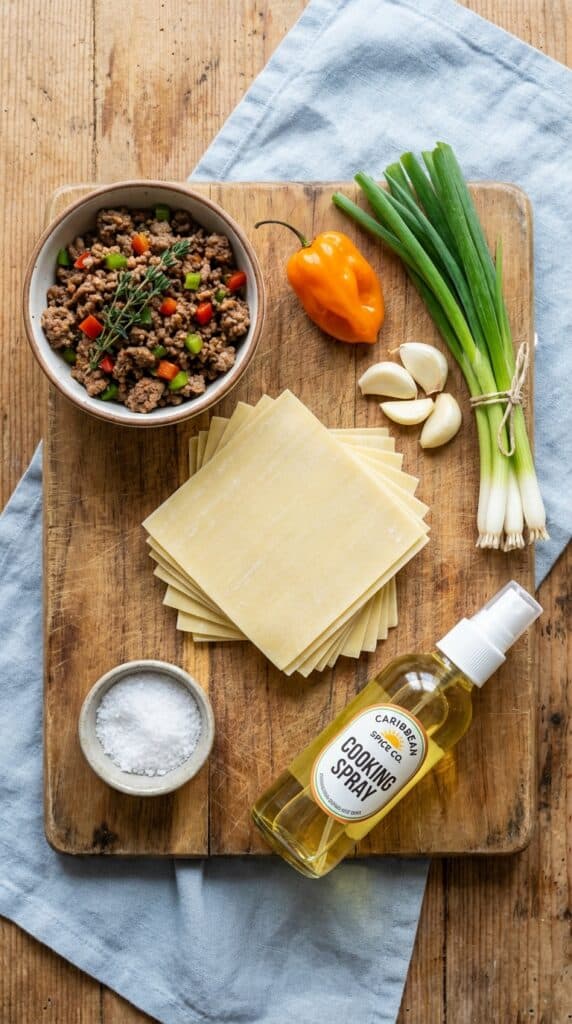 A flat lay showing wonton wrappers, seasoned meat filling, scallions, scotch bonnet peppers, and oil spray.