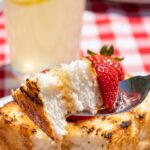 A close-up of a fork taking a bite of grilled cake, showing the toasted edge and soft interior.