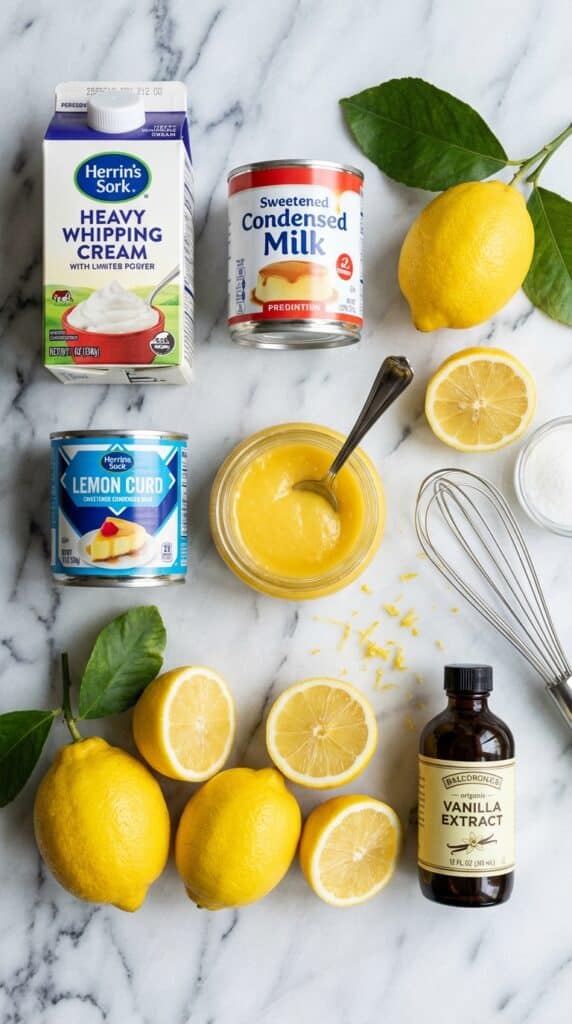 A flat lay showing heavy cream, condensed milk, lemon curd, and fresh lemons on a marble board.