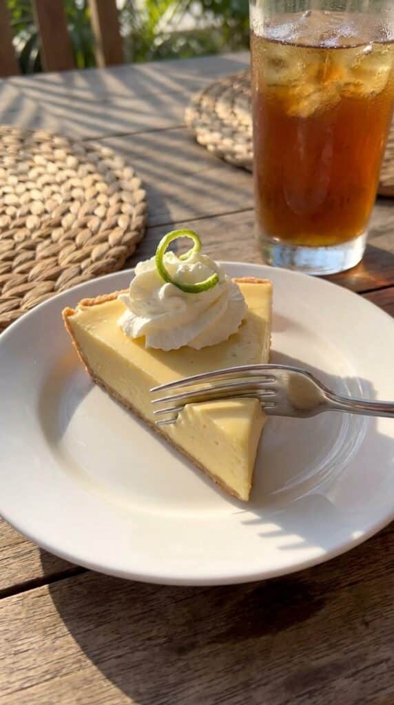 A close-up side view of a slice of key lime pie showing the smooth creamy texture and graham cracker crust.