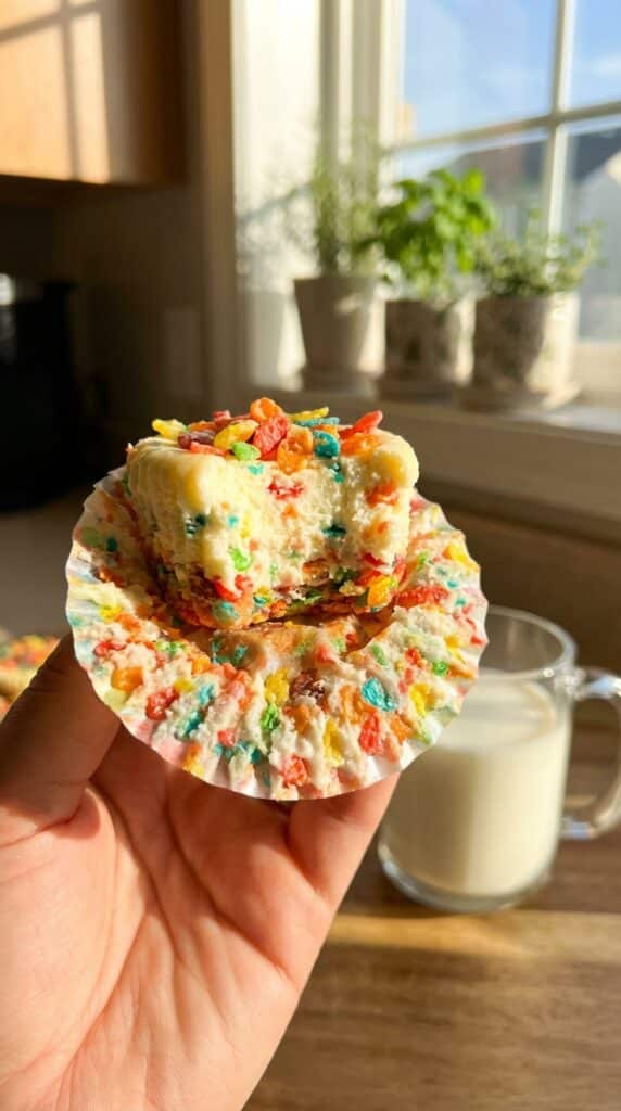 A close-up cross-section of a halved sweet potato cupcake, showing a moist orange interior and fluffy toasted marshmallow frosting.