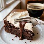 A close-up of a fork cutting into a slice of rich chocolate mud pie with whipped cream.