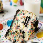 A close-up of a slice of funfetti cheesecake showing the creamy texture and sprinkles inside.