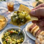 A close-up of a tortilla chip scooping up a large chunk of pickle salsa.