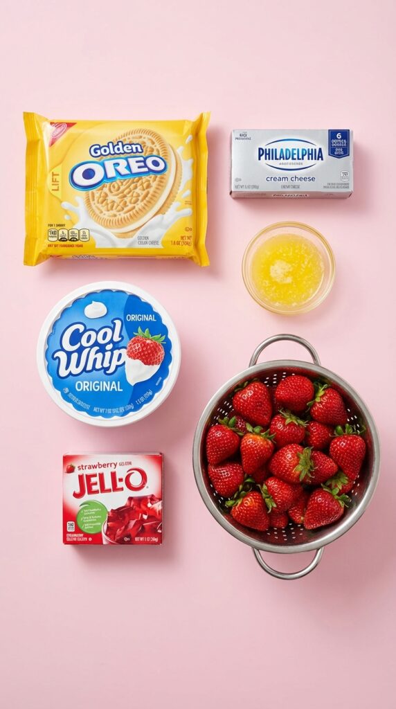 A flat lay showing Golden Oreos, cream cheese, cool whip, strawberry jello mix, and fresh strawberries on a pink surface.