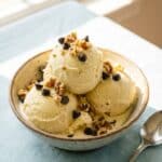 A close-up of a spoon scooping creamy banana ice cream, showing a soft-serve texture.