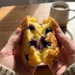 A close-up of hands tearing open a piece of fluffy blueberry cloud bread, showing the airy texture inside.