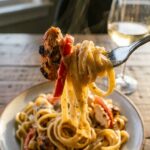 A close-up of a fork lifting creamy Cajun chicken and peppers with pasta.