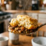 A baked beef cobbler topped with golden brown garlic cheddar biscuits brushed with butter and parsley.