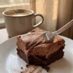 A flat lay of baking ingredients including chocolate chips, cocoa powder, heavy cream, eggs, and butter.