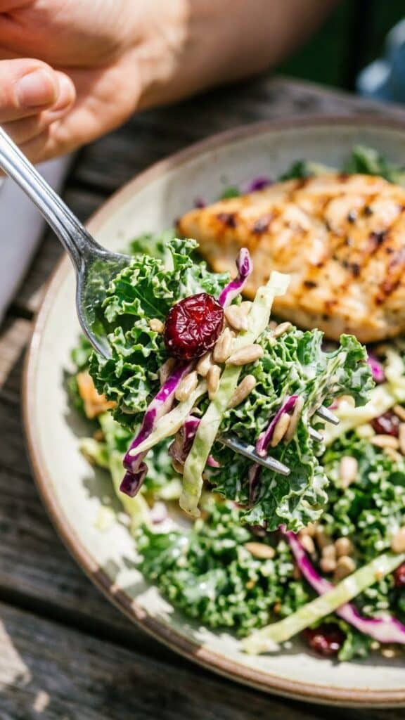 A close-up of a fork lifting a bite of crunchy kale salad with dressing and seeds.
