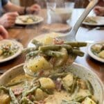 A close-up POV shot of a spoon lifting buttery ranch potatoes and green beans.