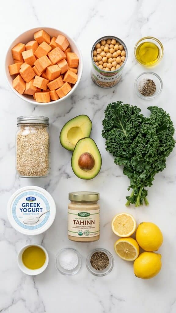 A flat lay showing sweet potatoes, chickpeas, quinoa, kale, yogurt, and tahini on a marble table.