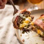 A close-up POV shot of a fork lifting a cheesy, saucy bite of jalapeño popper meatloaf drizzled with ranch.