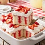 A close-up of a single slice of strawberry poke cake on a plate, showing the moist red and white crumb.