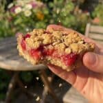 A flat lay showing fresh strawberries in a basket, rolled oats, brown sugar, flour, and butter on a marble surface.