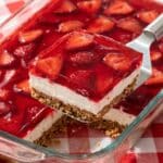 An overhead flat lay of ingredients including pretzels, cream cheese, jello box, strawberries, and butter on a wooden surface.