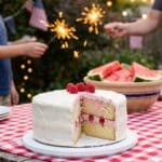 A patriotic poke cake served at a backyard 4th of July party with sparklers in the background.