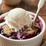 An intimate, appetizing shot of the dessert ready to be eaten, highlighting the temperature contrast between the hot fruit and cold ice cream.