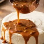 Pouring warm pecan praline sauce over a cheesecake.