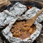 Close-up of a spork taking a bite of warm apple crisp.