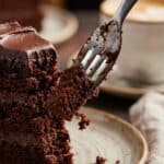 Close-up of a fork cutting into a tender slice of chocolate cake.