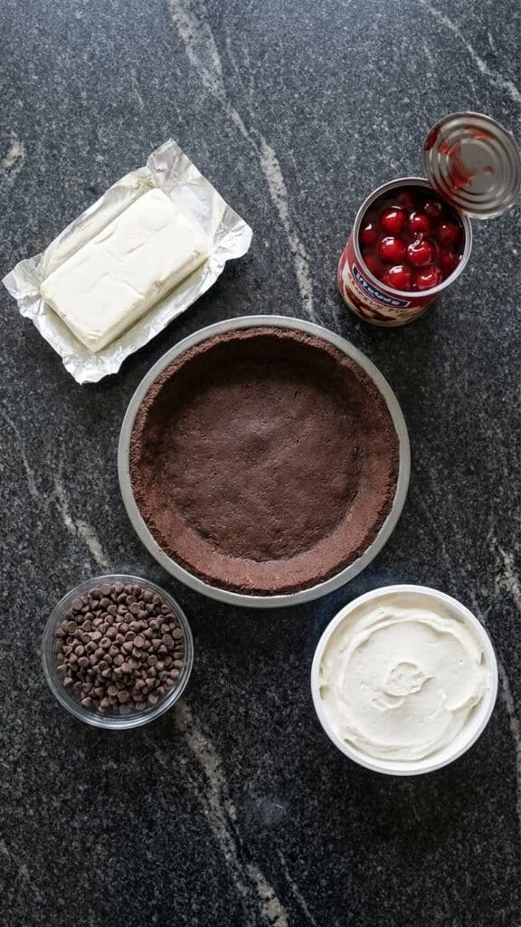 Ingredients for chocolate cherry pie including chocolate crust, cherry filling, cream cheese, and mini chips.