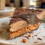 Close-up of a fork taking a bite of creamy Butterfinger pie.