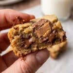 Close-up of a hand holding a chewy coconut toffee bar with a bite taken out.