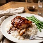 Plated Garlic-Brown Sugar Chicken Thigh served over white rice with green beans on a dinner table.