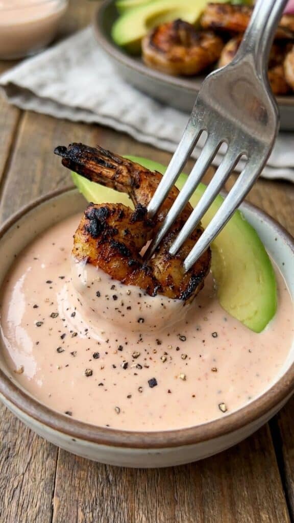 Close-up of grilled shrimp and avocado dipped in pink Louie dressing.