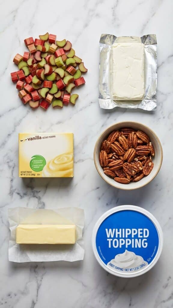 Flat lay of ingredients for layered rhubarb dessert including fresh rhubarb and pudding mix.