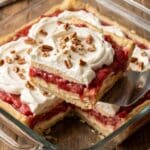 Overhead shot of a 9x13 pan of rhubarb layered dessert with a serving being removed.