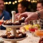 A tiered stand filled with chocolate brownie cheesecake cups at a party.