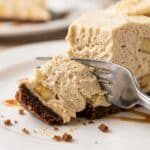 Close-up of a fork cutting into a creamy slice of no-bake banana cheesecake.