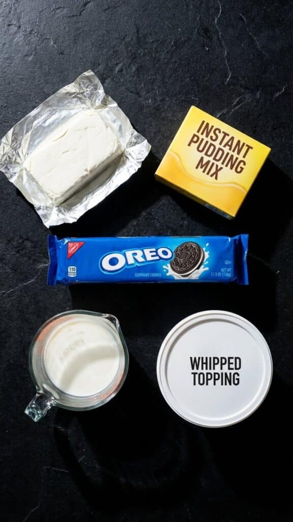 Ingredients for Oreo fluff including cookies, pudding mix, milk, cream cheese, and cool whip.