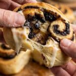 Close-up of a hand unrolling a soft, gooey Oreo cinnamon roll.