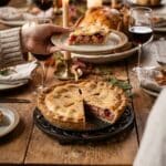 A pecan cheesecake pie being served at a Thanksgiving dinner table.