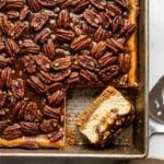Overhead shot of a pan of pecan cheesecake bars showing the glossy topping.