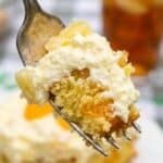 Close-up of a fork holding a bite of moist orange and pineapple cake.