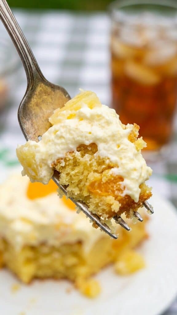 Close-up of a fork holding a bite of moist orange and pineapple cake.
