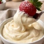 Close-up of a strawberry dipped in fluffy pudding mousse frosting.